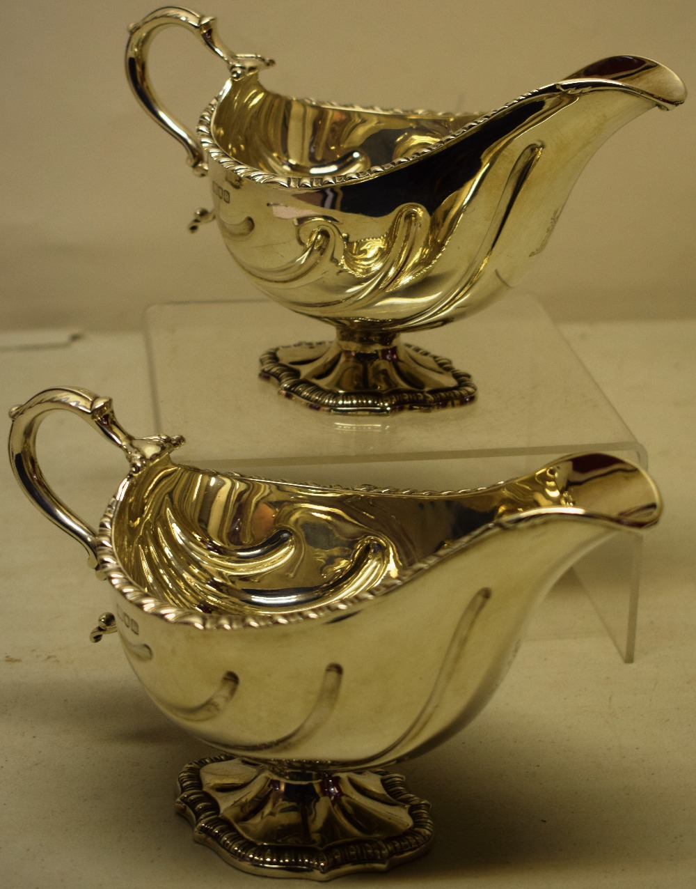 A pair of late Victorian silver oval sauceboats, with shell fluted bowls engraved a stags head