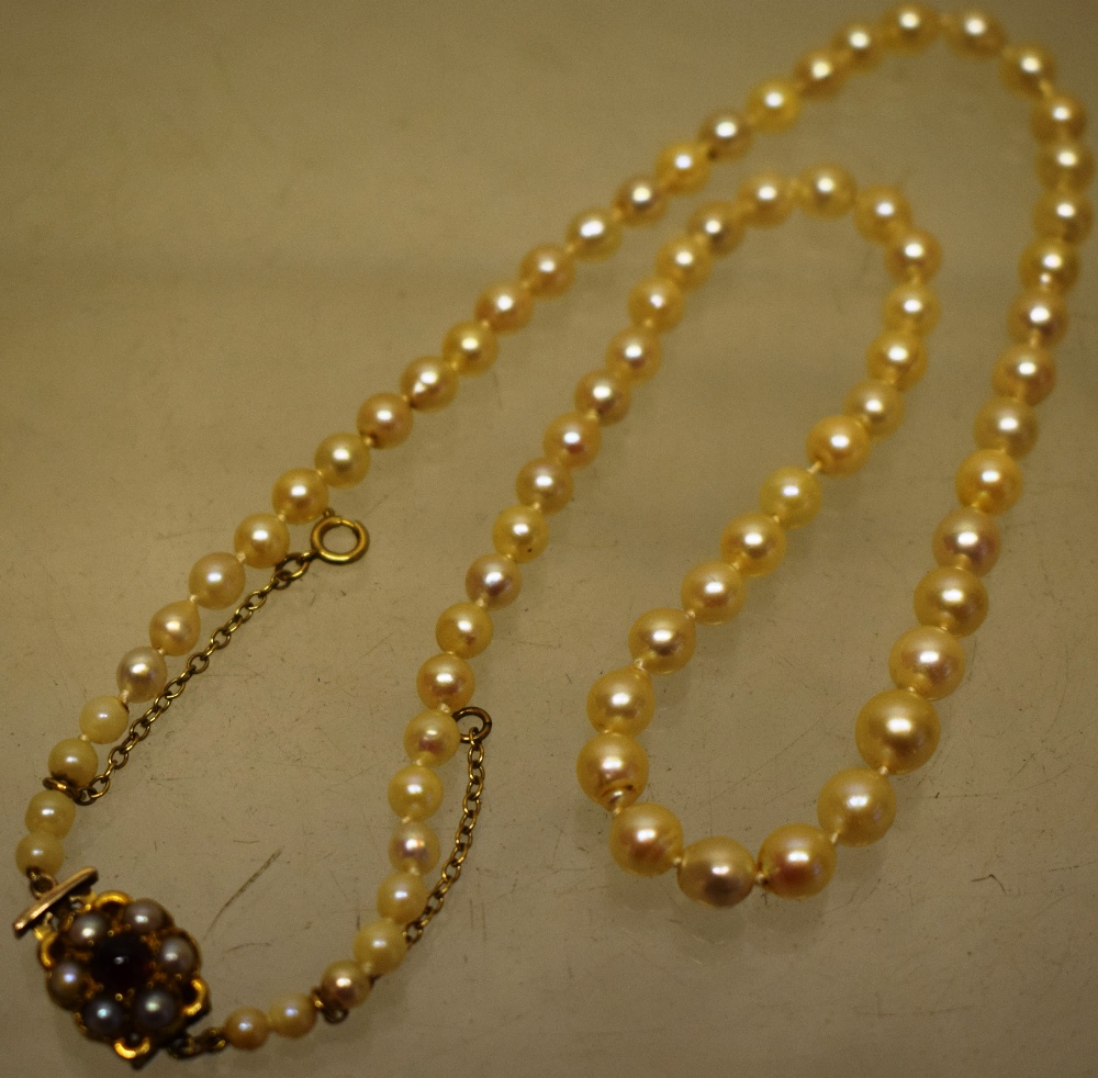 A vintage cultured pearl necklace, 17in (43cm) the pierced back gold snap set with a garnet and