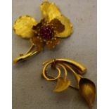 A red stone set, yellow gold coloured metal flower brooch, set small rubies in the centre bearing
