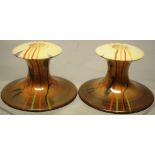 An unusual pair of Clarice Cliff Bizarre china dwarf candlesticks with candy stripes and foliage, to