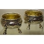 A pair of George II silver circular salts, the sides with repouse foliage and scallop shells,