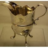A mid eighteenth century Irish silver cream jug, the helmet shape body with a serpentine border,