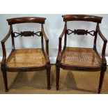 A pair of George IV mahogany elbow chairs, the backs and caned seat fronts with panels of carved