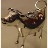 A continental silver cow creamer, the back with a floral chased hinged cover, an applied insect 5.