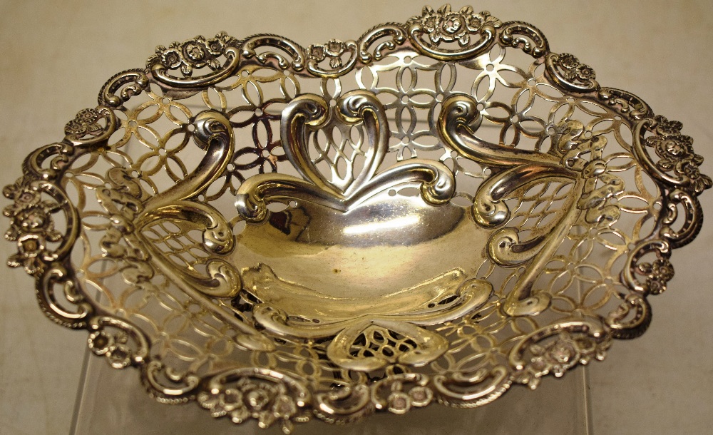 A late Victorian silver ovoid sweetmeat dish, the pierced fretwork sides with repousse scrolls, a