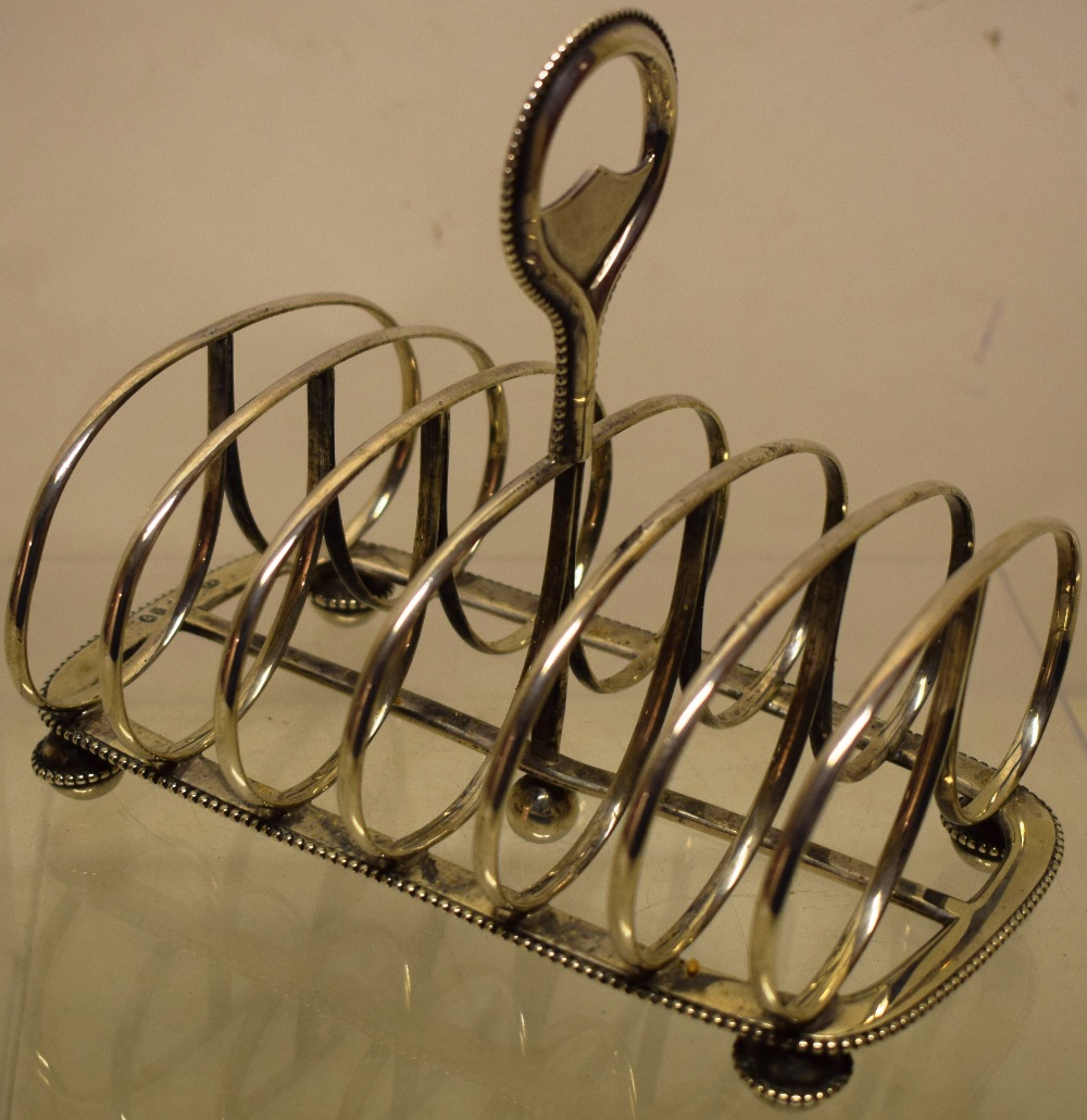 A Victorian silver toast rack, with beaded borders, the six divisions with a central ring handle, on