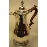 A George III silver baluster jug, having a fluted scroll spout with a leaf pendant, a hinged ogee