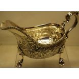 A large George IV silver sauceboat, the sides with contemporary chased and repousse foliage, with