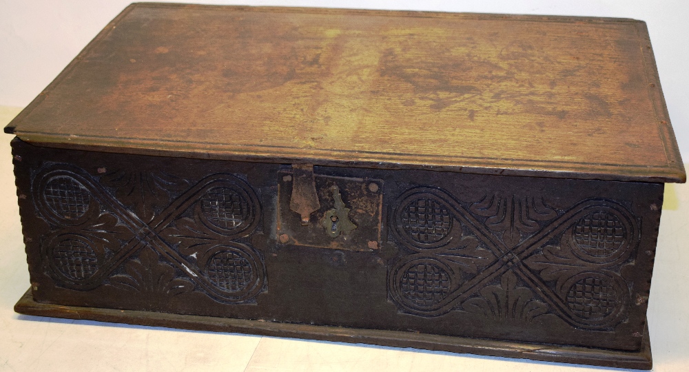 A seventeenth century oak bible box, the interior with a lidded candlebox, the front carved with