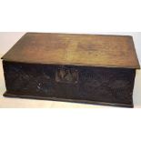 A seventeenth century oak bible box, the interior with a lidded candlebox, the front carved with