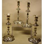 A set of four George II cast silver candlesticks, the reeded spool shape candleholders with