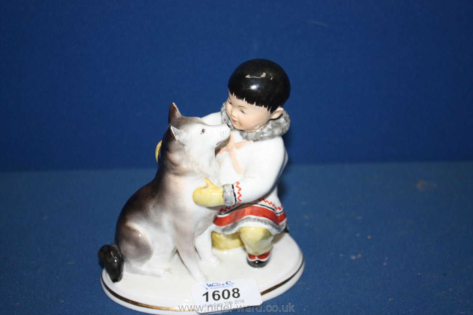 A Russian figure of a young Eskimo boy with his Husky dog.