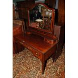 An Edwardian Mahogany Kneehole Dressing Table having shaped bevel plated mirror in finial topped