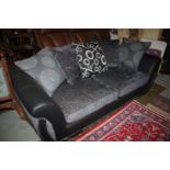 A large modern two seater Settee in black leather and charcoal fabric upholstery.