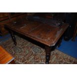 An Edwardian Oak wind-out extending Dining Table with three narrow leaves and winding handle,