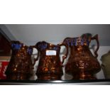 Three graduated copper Lustre Jugs with blue trim,