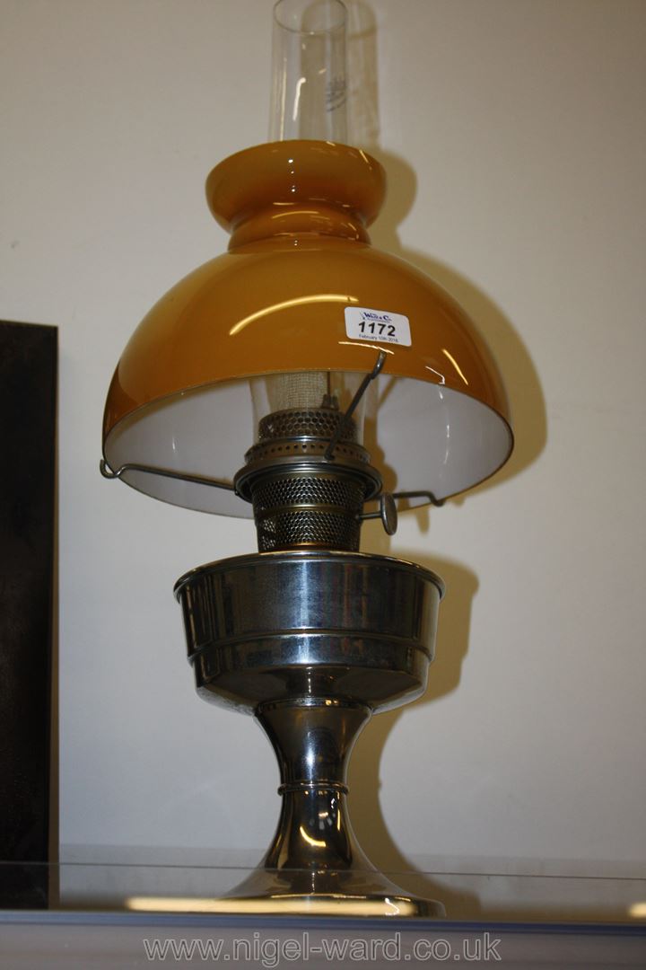 A chrome oil mantle lamp with mustard coloured shade.