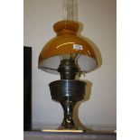 A chrome oil mantle lamp with mustard coloured shade.