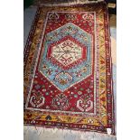 A Turkish style Rug in dark reds, blue and amber colours,