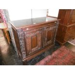 AN OAK CABINET WITH EARLY CARVED PANELS