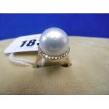 A ROSE METAL MARKED 750 PEARL RING WITH DIAMOND SET HALO