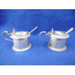 A PAIR OF EDWARDIAN GOLDSMITHS AND SILVERSMITHS HALLMARKED SILVER MUSTARD POTS WITH SPOONS,