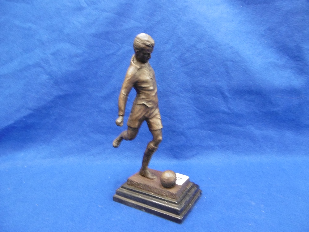 A BRONZE SCULPTURE OF A FOOTBALLER