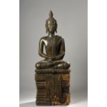 Buddha assis en virasana sur un haut socle à base lotiforme d'où pend une [...]