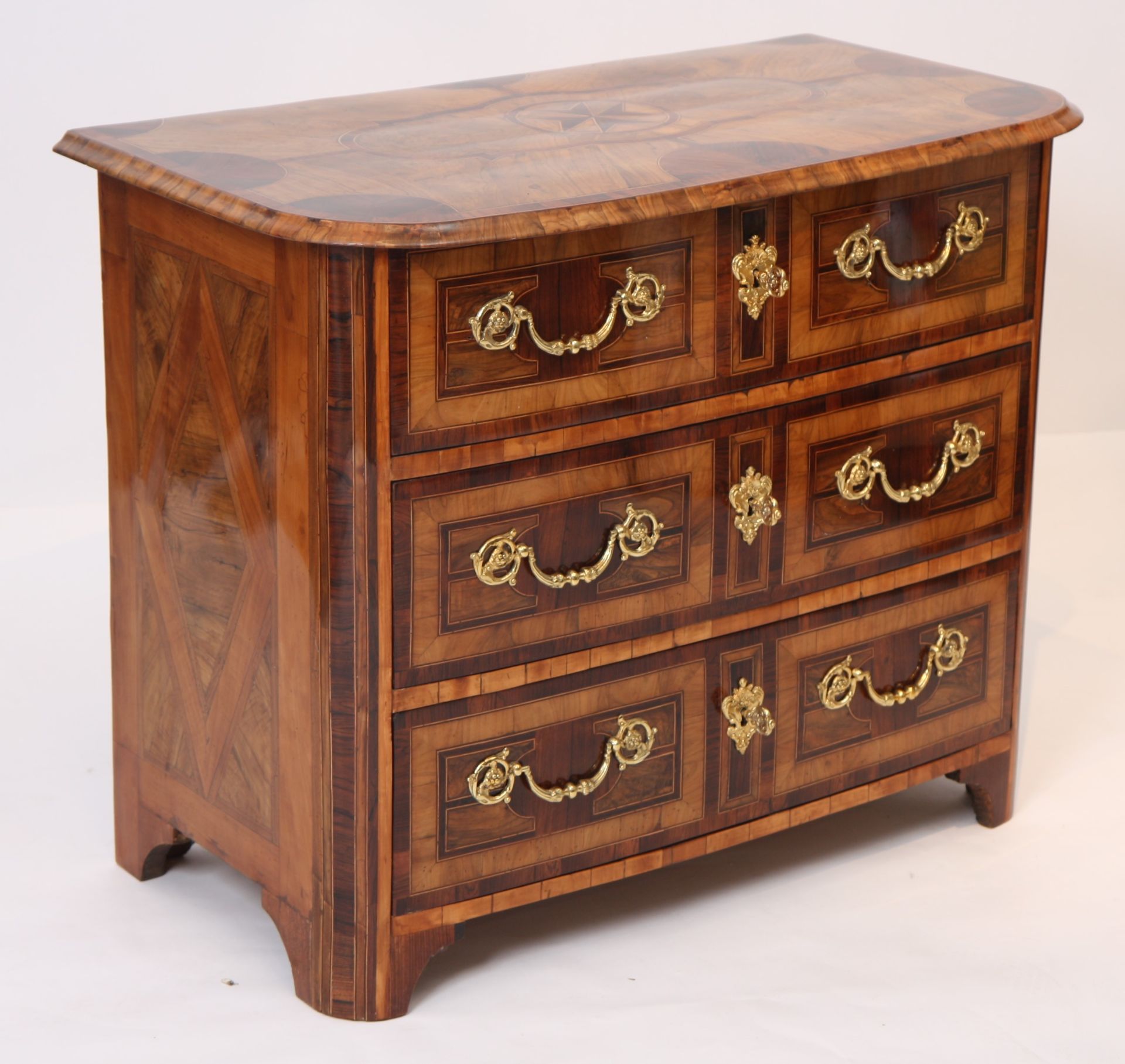 RARE PETITE COMMODE MARQUETEE LOUIS XIV En plaquage de bois indigènes, à décors [...]