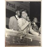 JAMES BROWN SIGNED PHOTO. A black and white photograph of James Brown on stage, pasted onto card.