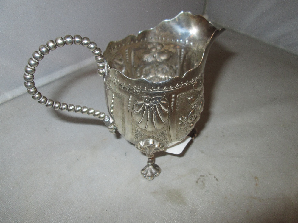 Solid silver cream jug with repousse foliate decoration on three scallop feet Sheffield 1865