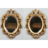 A pair of 19th century small oval giltwood pier glasses with bevelled mirror plates and adorned