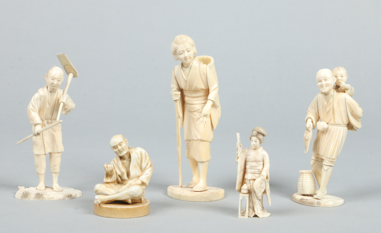 A Japanese Meiji period carved ivory okimono formed as a bijin holding a fan and a scroll, signed.