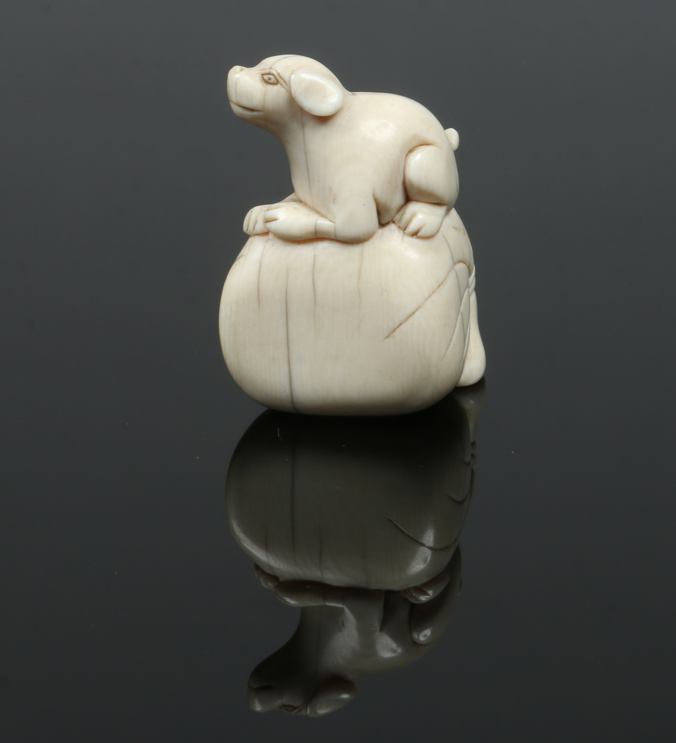 A Japanese Meiji period carved ivory netsuke. Formed as a dog seated upon a large sack, 4.5cm high.