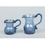 Two early 19th century blue glass cream jugs with bubble inclusions,