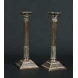 A pair of George V silver table candlesticks of fluted Corinthian column form,