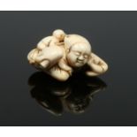 A Japanese Edo period carved ivory netsuke formed as a sleeping man with a monkey stealing nuts