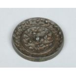 A small Japanese silvered bonze roundel mirror. Decorated in relief to the reverse side, 7.75cm.