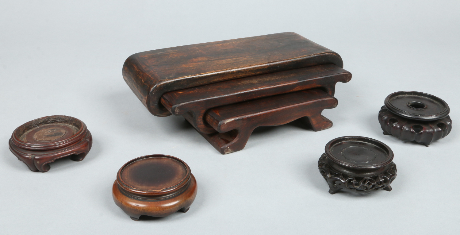 Four Chinese carved hardwood small ornament stands and a Japanese hardwood nest of three stands.