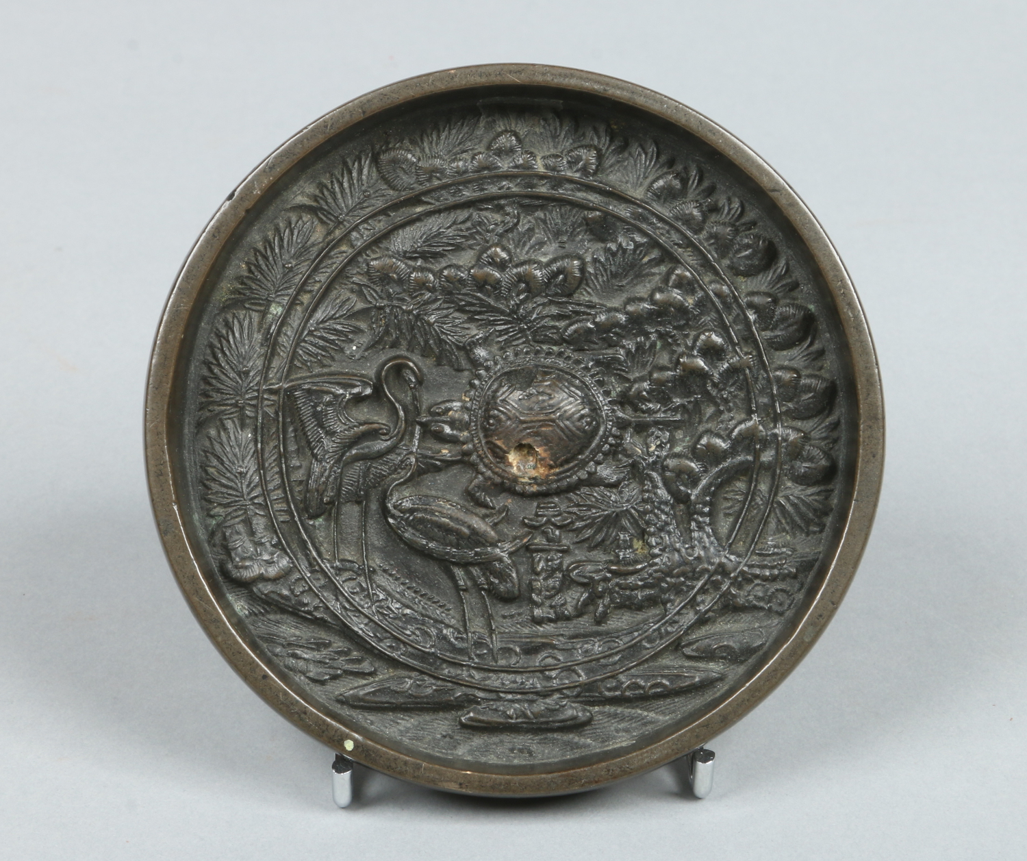 A Japanese Meiji period patinated bronze small mirror of roundel form.