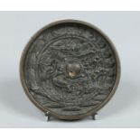 A Japanese Meiji period patinated bronze small mirror of roundel form.