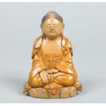 A Chinese earthenware figure of a seated meditating Buddha raised on a lotus plinth and in ochre