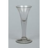 A Georgian wine glass with bell shaped bowl raised on a plain stem containing a small tear, 16.25cm.