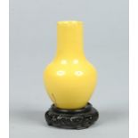 A Chinese miniature earthenware bottle vase decorated in canary yellow glaze and raised on a