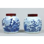 A pair of 18th century Chinese blue and white ginger jars with associated hardwood covers.