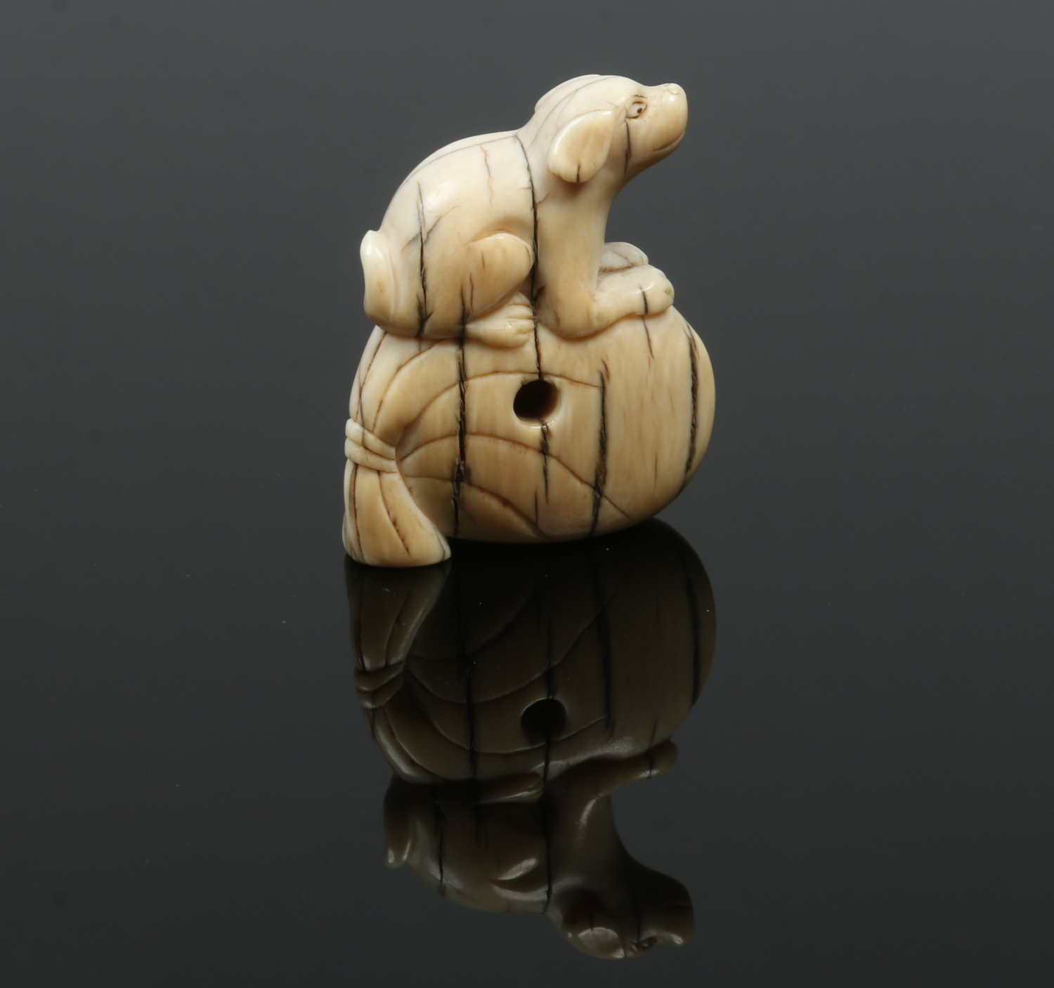 A Japanese Meiji period carved ivory netsuke. Formed as a dog seated upon a large sack, 4.5cm high. - Image 2 of 2