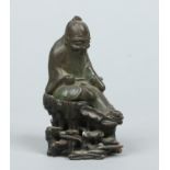 An 18th / 19th century Chinese small verdigris bronze figure of a seated sage holding a scroll and