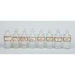 Eight Victorian glass chemists jars and stoppers with gilt and red edged canted rectangular labels,