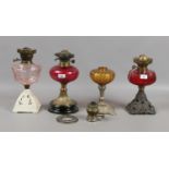 Four Victorian oil lamp bases, two with cranberry glass fonts. some damaged.