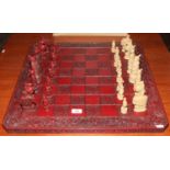 A Chinese style chess set with carved and painted board and composite pieces.